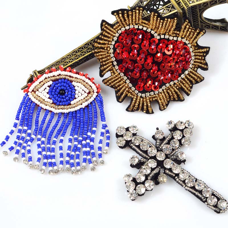 Collection of premium handmade beaded patches and crystal rhinestone badges, including evil eye, heart, and cross motifs