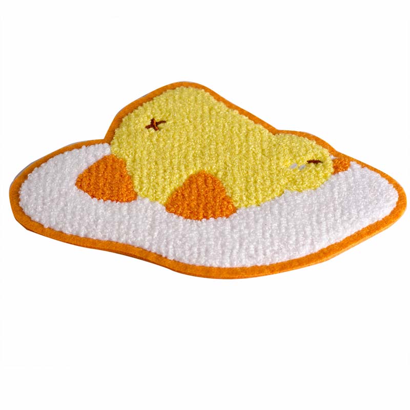 Front flat lay view of an oval cartoon duck fried egg chenille patch with hot-melt adhesive backing